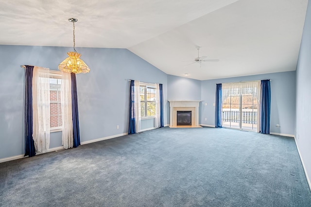 unfurnished living room with a glass covered fireplace, plenty of natural light, ceiling fan with notable chandelier, and carpet floors