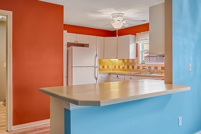 kitchen featuring tasteful backsplash, ceiling fan, a peninsula, white cabinets, and white appliances