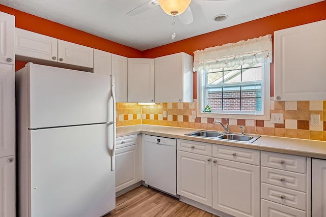 kitchen with white appliances, a sink, light countertops, white cabinets, and tasteful backsplash