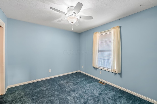 empty room featuring visible vents, dark carpet, a healthy amount of sunlight, and ceiling fan