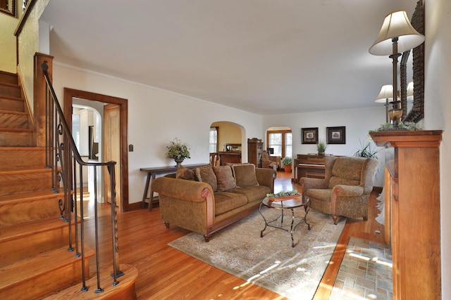 living room with stairway, wood finished floors, arched walkways, and baseboards