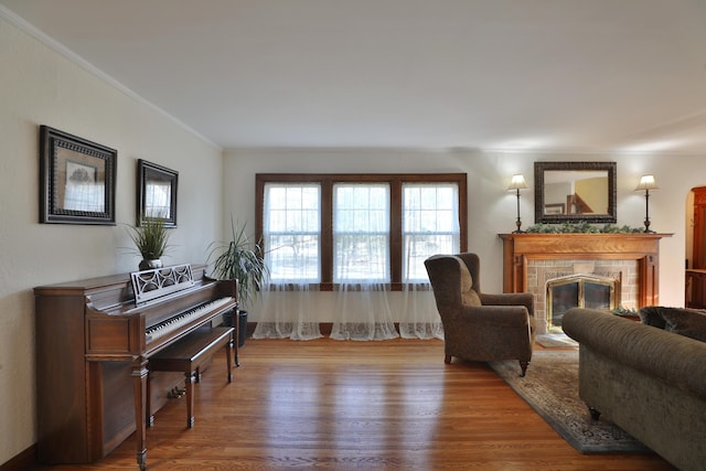 living room with wood finished floors, crown molding, and a tiled fireplace