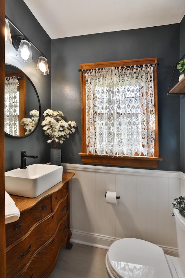 bathroom featuring vanity, toilet, and wainscoting