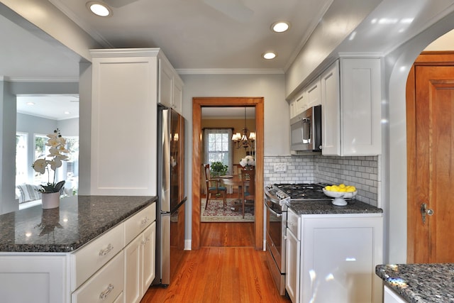 kitchen with crown molding, backsplash, light wood-type flooring, and appliances with stainless steel finishes