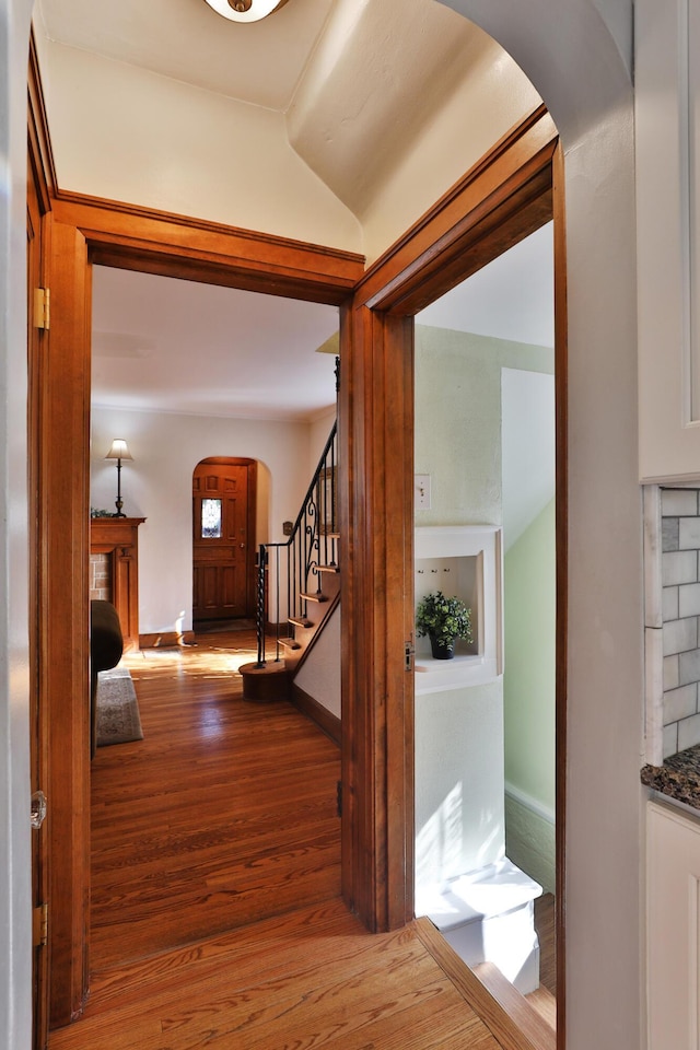 interior space with stairway, arched walkways, baseboards, and wood finished floors