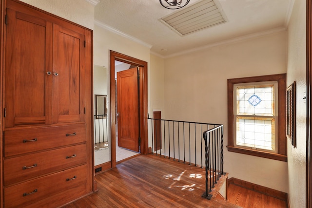 corridor with visible vents, baseboards, dark wood-style flooring, crown molding, and an upstairs landing