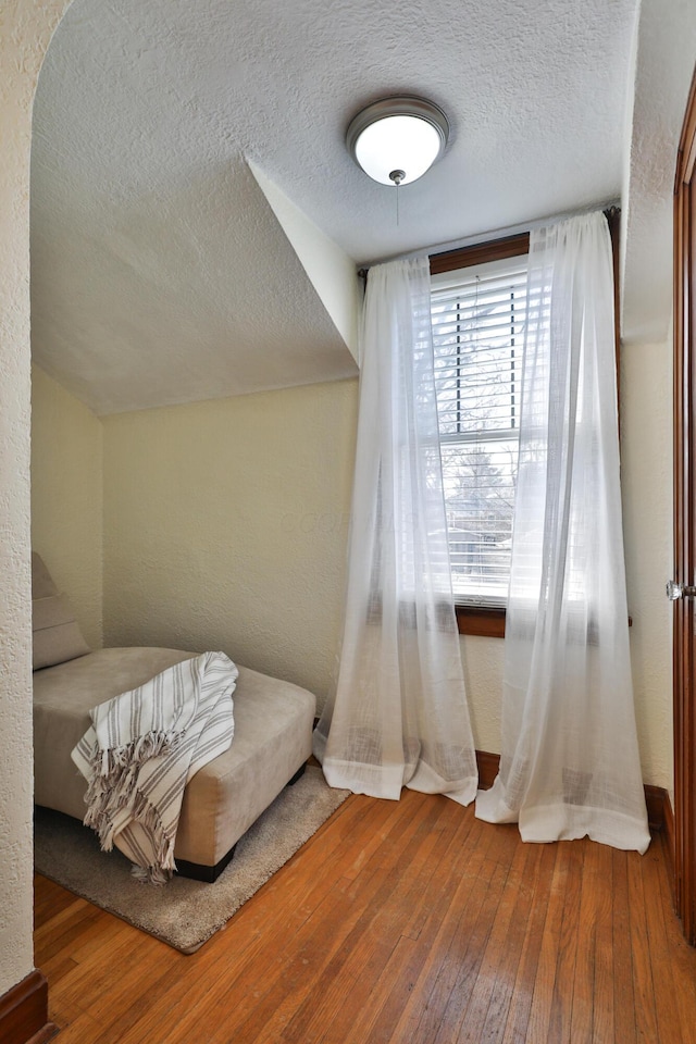 bedroom featuring hardwood / wood-style floors, a textured wall, and a textured ceiling