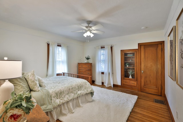 bedroom with visible vents, multiple windows, wood finished floors, and a ceiling fan