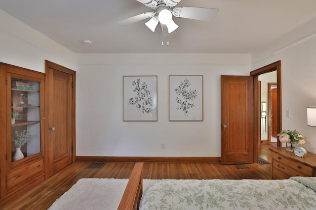 bedroom featuring ceiling fan, visible vents, baseboards, and wood finished floors