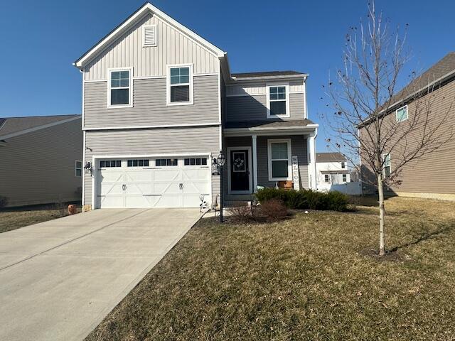 traditional-style home featuring a front lawn, an attached garage, board and batten siding, and driveway