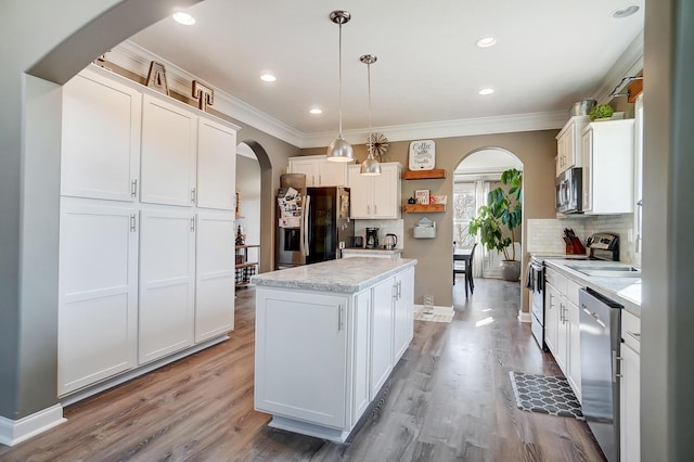 kitchen with open shelves, white cabinets, arched walkways, and appliances with stainless steel finishes