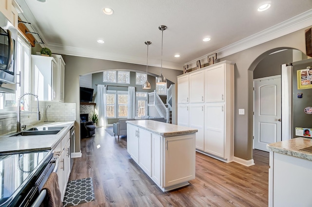 kitchen featuring a sink, arched walkways, backsplash, and crown molding