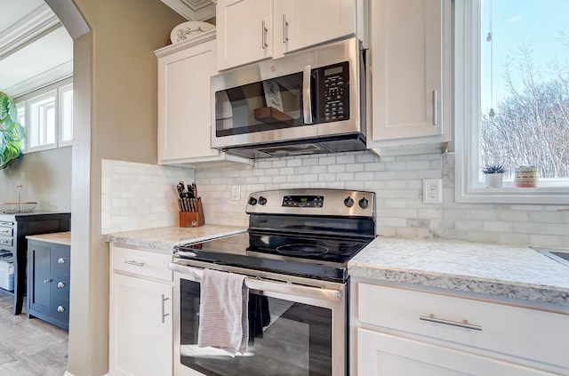 kitchen featuring light stone counters, backsplash, appliances with stainless steel finishes, and white cabinetry