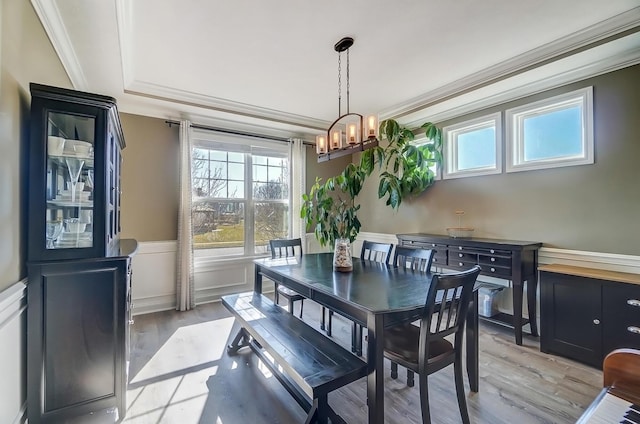 dining space with crown molding, light wood-style floors, a chandelier, and wainscoting