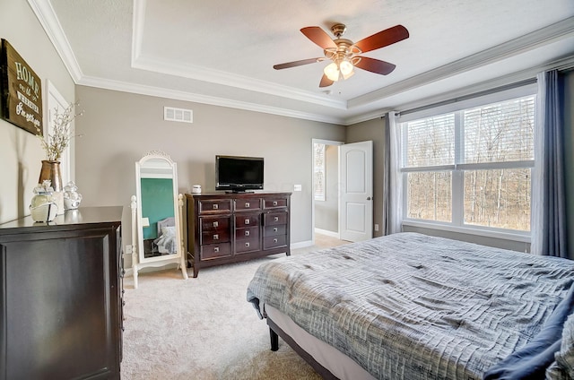 bedroom with a raised ceiling, light colored carpet, visible vents, and ornamental molding