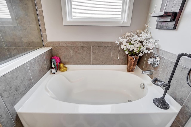 bathroom featuring a garden tub and a healthy amount of sunlight