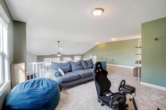 living area featuring vaulted ceiling, a textured ceiling, baseboards, and carpet floors