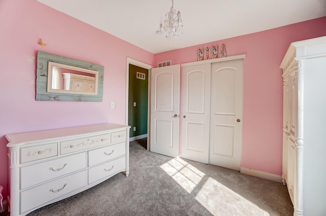 unfurnished bedroom featuring visible vents, light colored carpet, a closet, and a notable chandelier