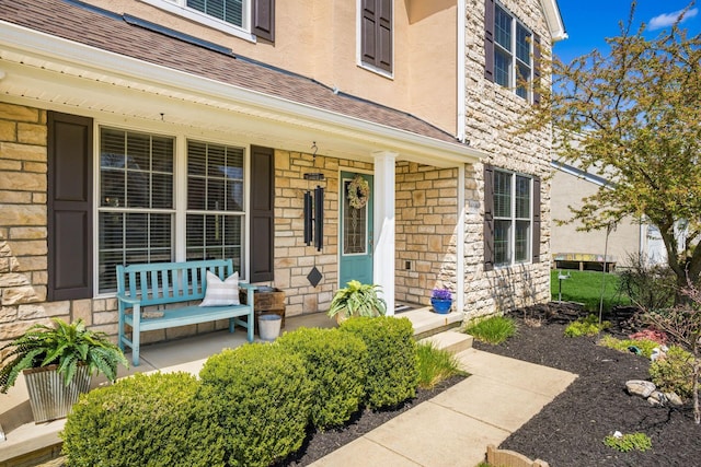 6148 Ryan Woods Way, Hilliard, OH 43026 - property entrance featuring stone siding, a shingled roof, covered porch, and stucco siding