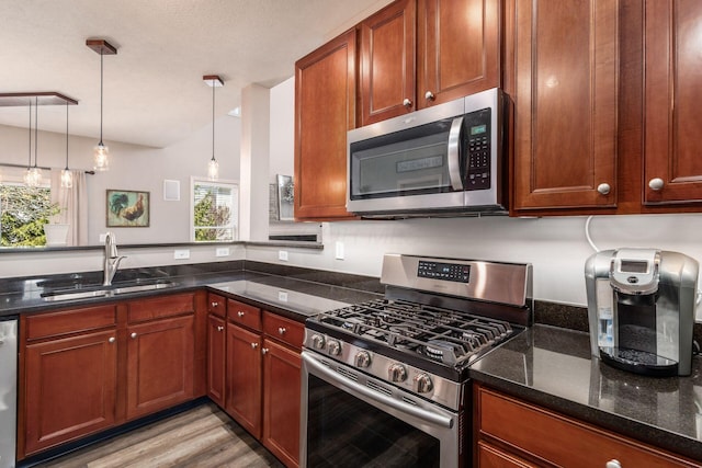 6148 Ryan Woods Way, Hilliard, OH 43026 - kitchen with a sink, dark stone counters, light wood-style floors, pendant lighting, and appliances with stainless steel finishes