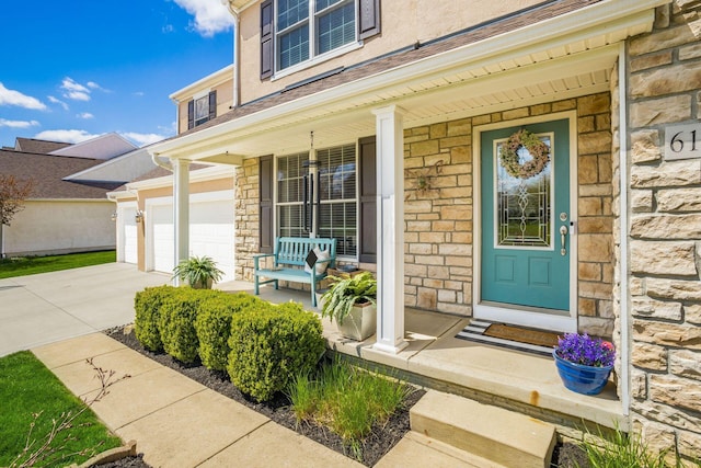 6148 Ryan Woods Way, Hilliard, OH 43026 - view of exterior entry with a garage, driveway, stone siding, and covered porch
