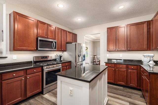 6148 Ryan Woods Way, Hilliard, OH 43026 - kitchen with a kitchen island, wood finished floors, a textured ceiling, and stainless steel appliances