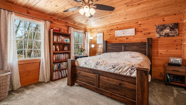 carpeted bedroom with wooden walls, wood ceiling, and ceiling fan