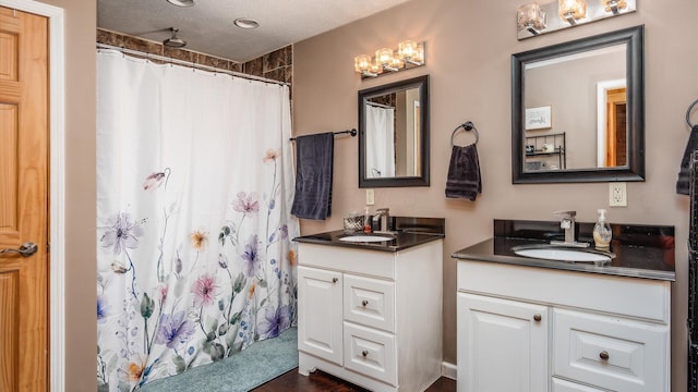 bathroom featuring a shower with shower curtain, two vanities, an inviting chandelier, a textured ceiling, and a sink