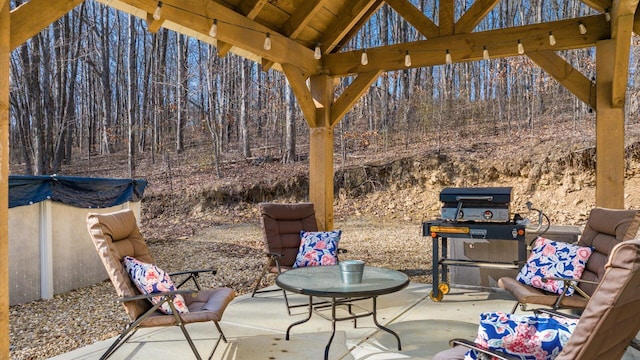 view of patio with a wooded view and grilling area