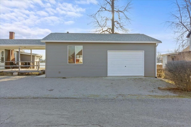 view of front of home with an outbuilding, a garage, driveway, and roof with shingles