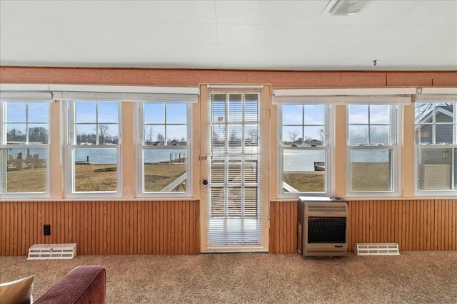 unfurnished sunroom featuring heating unit, plenty of natural light, and visible vents