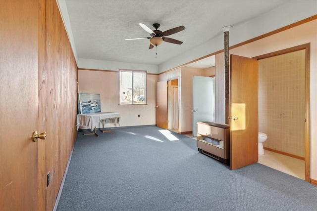 unfurnished bedroom with heating unit, carpet flooring, connected bathroom, and a textured ceiling