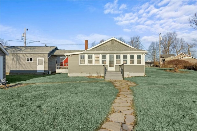 back of house featuring a lawn and a chimney