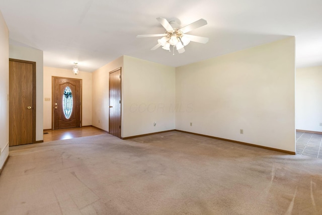 interior space with light colored carpet, a ceiling fan, and baseboards