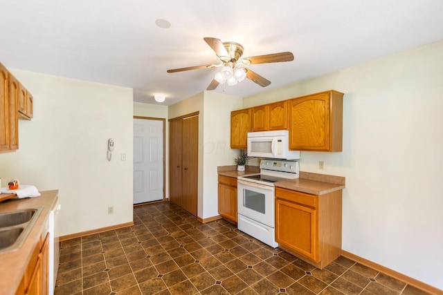 kitchen featuring white appliances, baseboards, a sink, ceiling fan, and light countertops