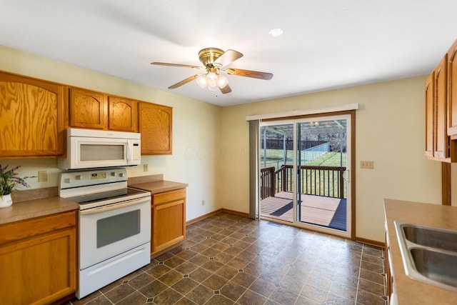 kitchen featuring white appliances, baseboards, a sink, ceiling fan, and brown cabinets