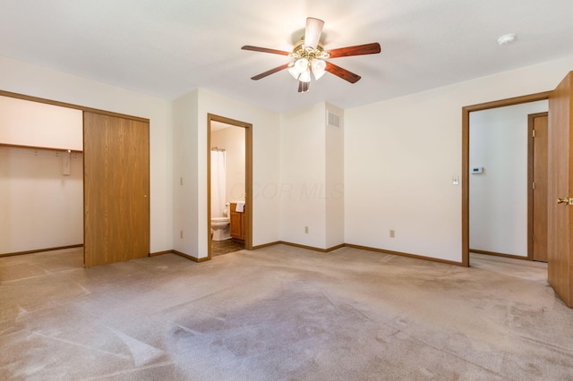 unfurnished bedroom with visible vents, light colored carpet, ensuite bathroom, and baseboards