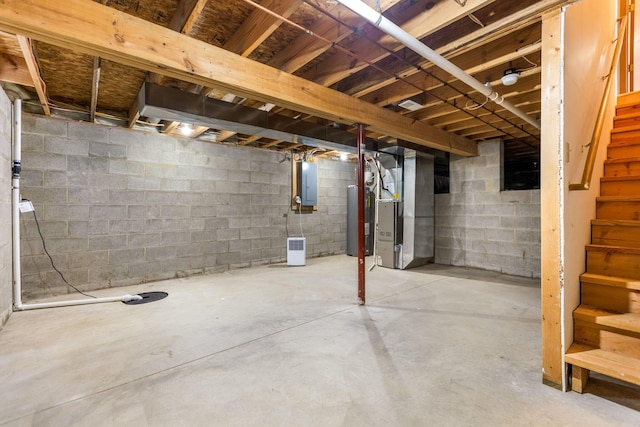 unfinished below grade area featuring electric panel, heating unit, water heater, and stairs