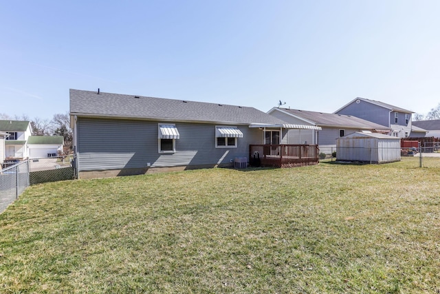 back of house featuring an outbuilding, a yard, a fenced backyard, and a shingled roof