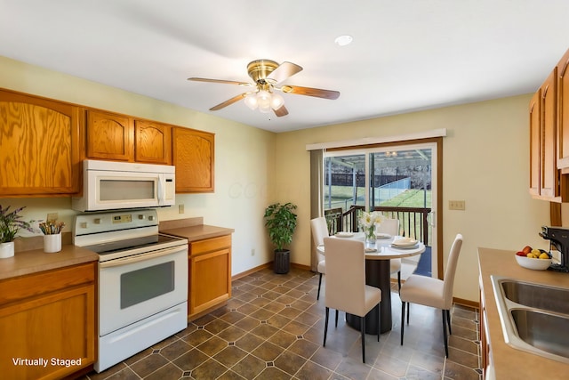 kitchen featuring brown cabinets, a sink, white appliances, light countertops, and baseboards