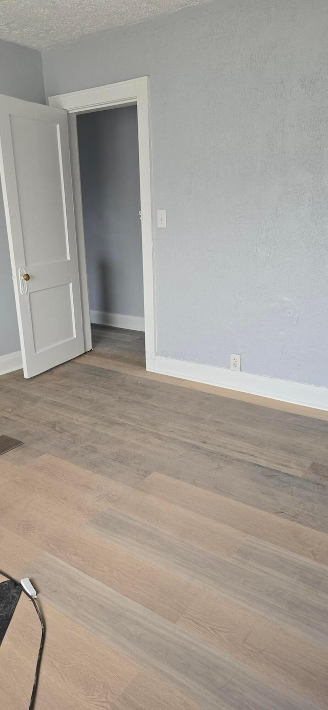 spare room with baseboards and wood finished floors