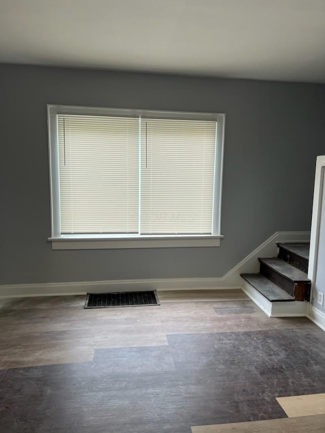 unfurnished room featuring visible vents, baseboards, wood finished floors, and stairway