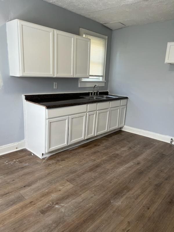 kitchen featuring baseboards, dark wood-style flooring, and a sink