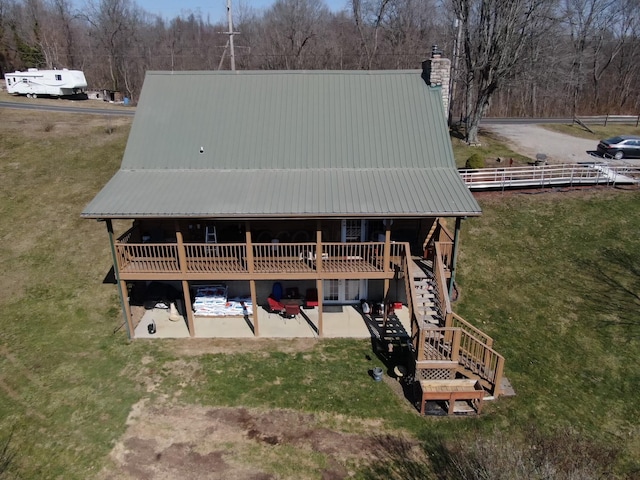 exterior space featuring a lawn, a chimney, stairs, and metal roof