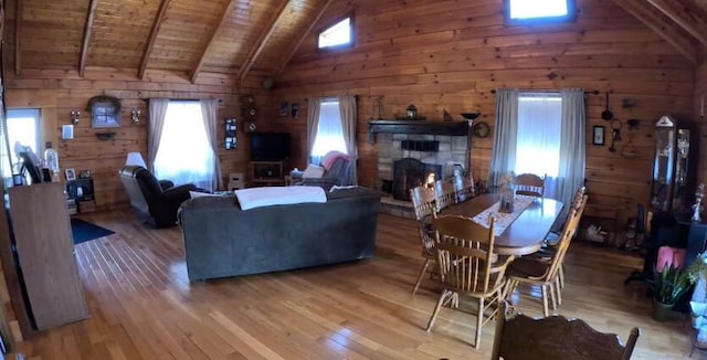 dining room with beamed ceiling, light wood finished floors, wood ceiling, and wood walls