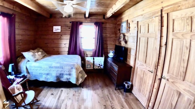 bedroom featuring beamed ceiling, wood walls, wooden ceiling, and hardwood / wood-style floors