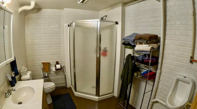 full bath featuring a shower stall, brick wall, toilet, and vanity