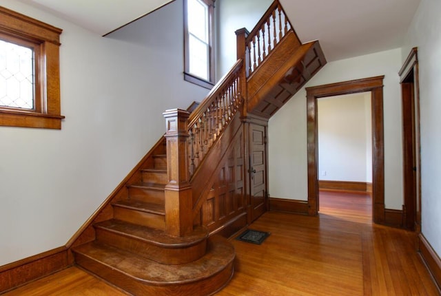 stairway with visible vents, baseboards, and wood finished floors