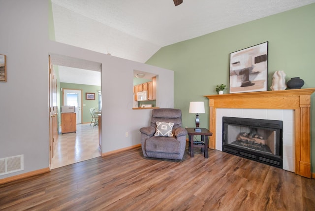 sitting room featuring visible vents, wood finished floors, a fireplace, baseboards, and vaulted ceiling