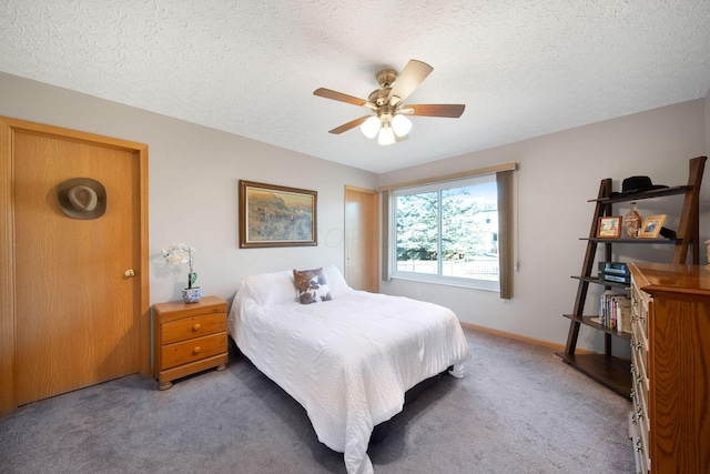 carpeted bedroom with ceiling fan, baseboards, and a textured ceiling